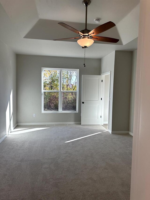 spare room featuring ceiling fan, a raised ceiling, and light carpet