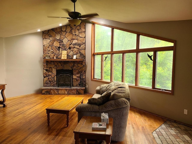 living area with vaulted ceiling, light wood-type flooring, a fireplace, and a ceiling fan