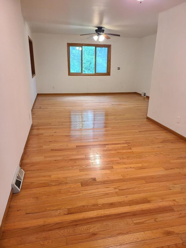 spare room with light wood-style floors, visible vents, ceiling fan, and baseboards