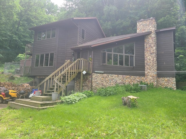 rear view of property with a chimney, stairway, and a lawn