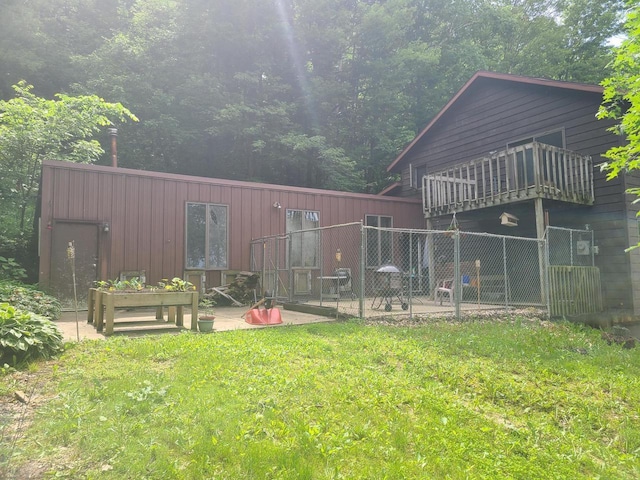 rear view of property featuring a lawn, a balcony, and a patio