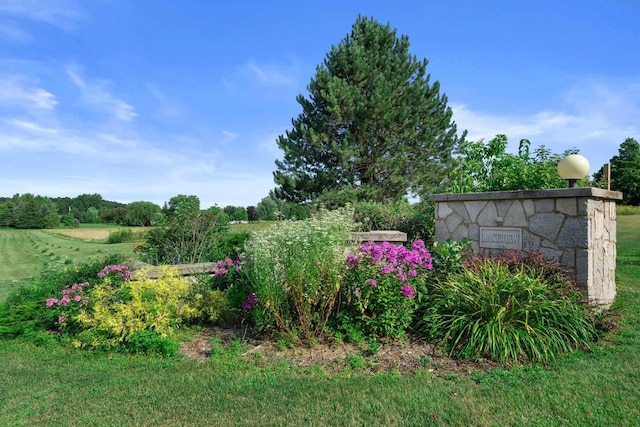 community / neighborhood sign with a lawn and a rural view