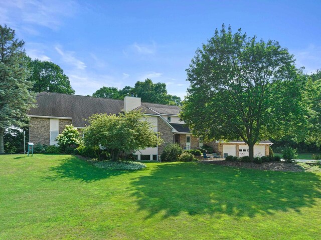 rear view of property featuring a garage and a lawn