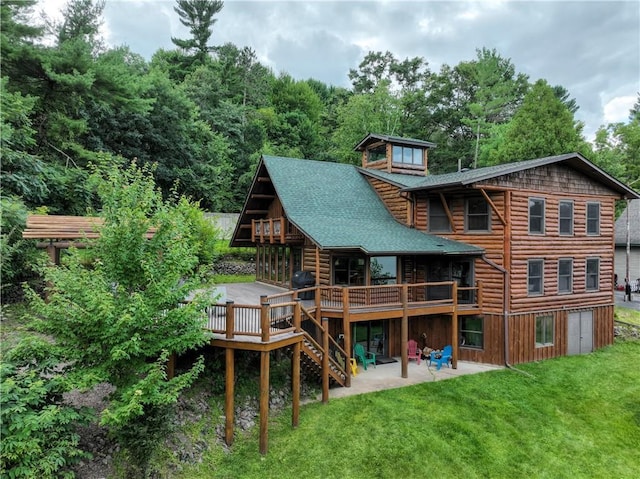 rear view of house featuring a wooden deck, a yard, and a patio