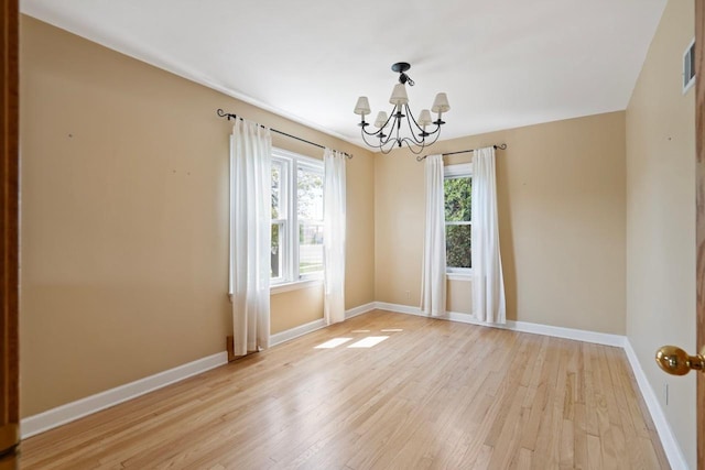 spare room with an inviting chandelier and light hardwood / wood-style flooring