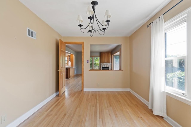 unfurnished dining area with light hardwood / wood-style floors and a chandelier