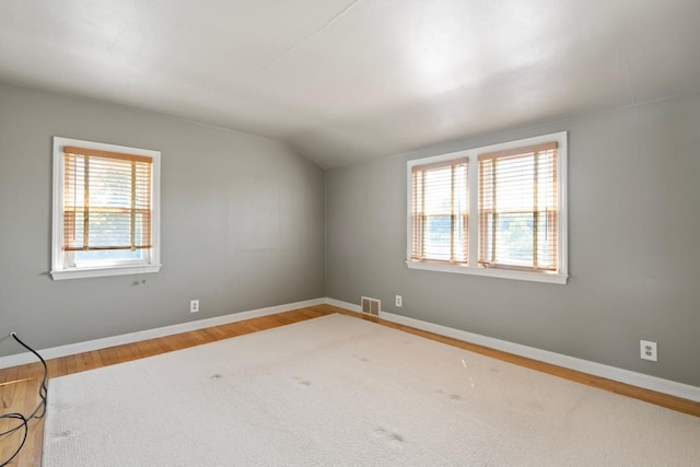 spare room with lofted ceiling, hardwood / wood-style floors, and a wealth of natural light