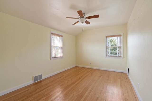 spare room with ceiling fan, a wealth of natural light, vaulted ceiling, and light wood-type flooring