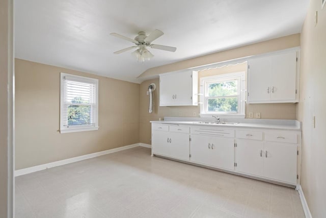 kitchen with sink, vaulted ceiling, white cabinets, and ceiling fan