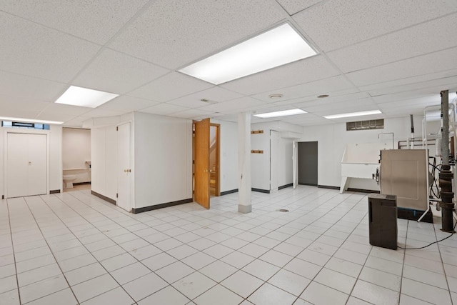 basement with a drop ceiling and light tile patterned flooring