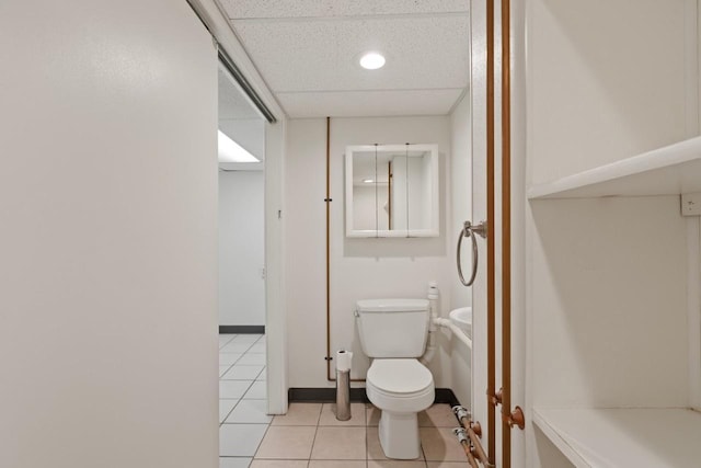 bathroom featuring a paneled ceiling, toilet, and tile patterned flooring