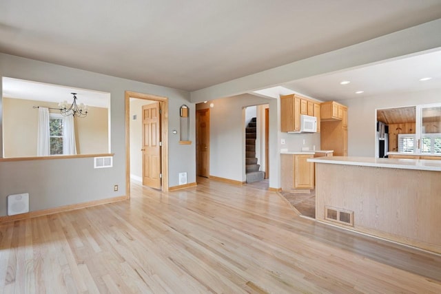 unfurnished living room with a notable chandelier and light wood-type flooring