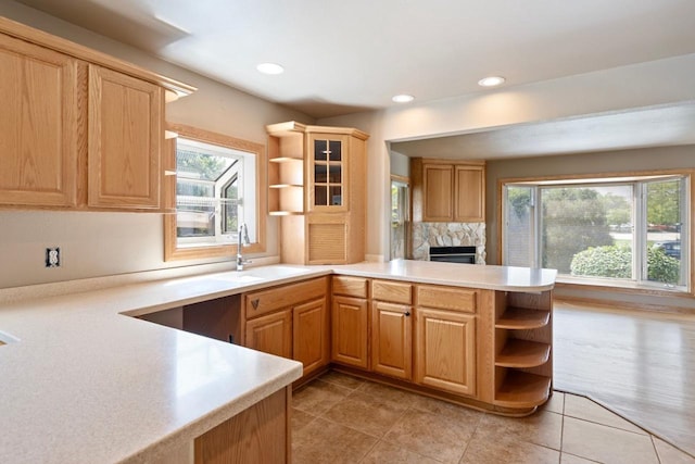 kitchen featuring sink, light tile patterned floors, a high end fireplace, and kitchen peninsula