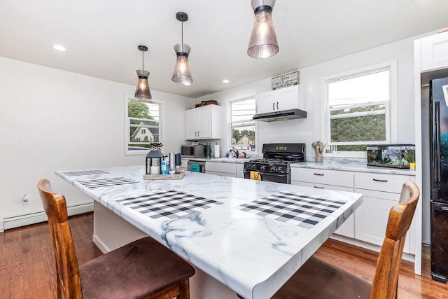 kitchen featuring white cabinets, light stone counters, dark hardwood / wood-style flooring, black gas stove, and pendant lighting