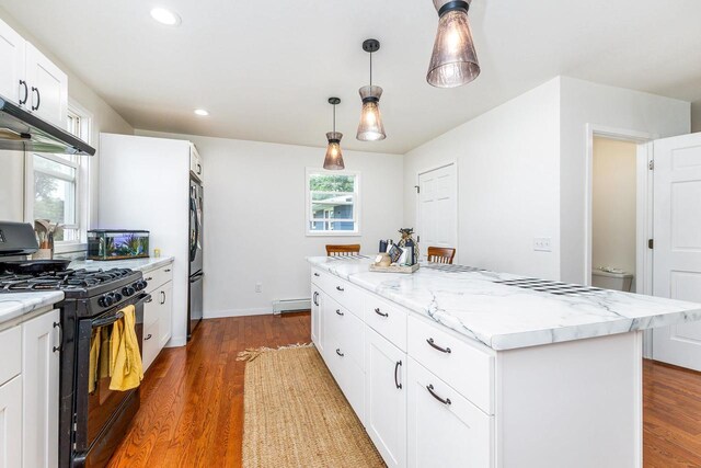 kitchen featuring gas stove, a center island, light stone counters, hanging light fixtures, and wood-type flooring