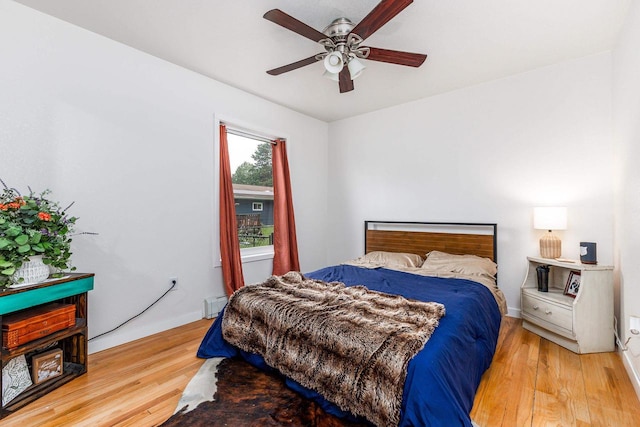 bedroom with a baseboard heating unit, light wood-type flooring, and ceiling fan