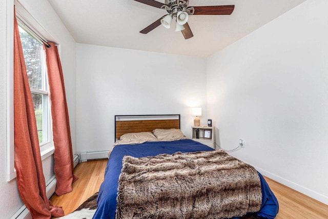 bedroom with a baseboard radiator, light hardwood / wood-style flooring, and ceiling fan