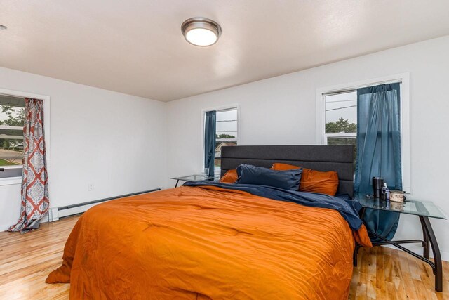 bedroom featuring multiple windows, light hardwood / wood-style flooring, and baseboard heating