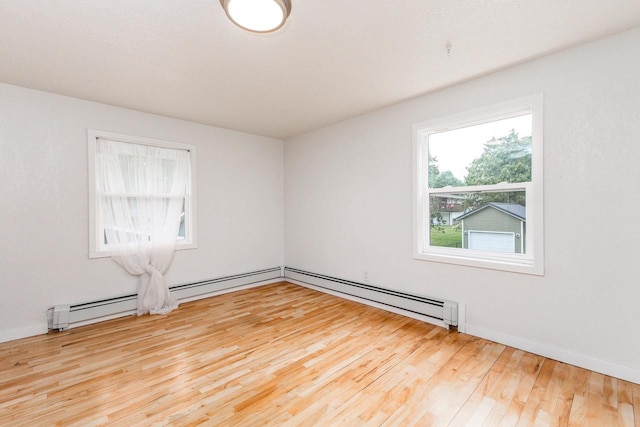 unfurnished room featuring light hardwood / wood-style flooring, a baseboard radiator, and a wealth of natural light