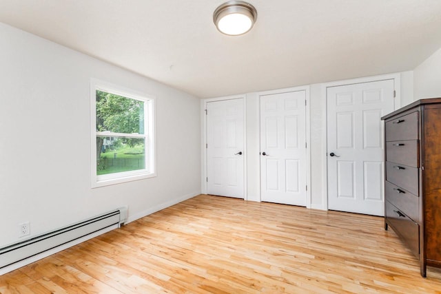 unfurnished bedroom featuring multiple closets, light hardwood / wood-style flooring, and baseboard heating