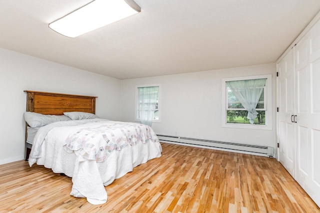 bedroom featuring baseboard heating, multiple windows, and light wood-type flooring