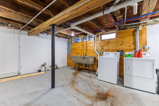 basement with sink, independent washer and dryer, and wooden walls