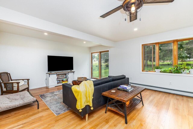 living room with a baseboard heating unit, light hardwood / wood-style floors, and ceiling fan