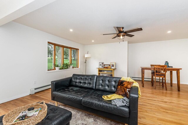 living room with a baseboard heating unit, light wood-type flooring, and ceiling fan