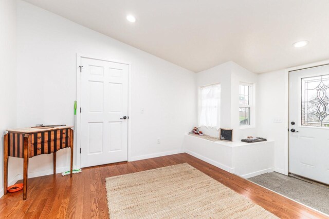 foyer entrance with wood-type flooring and lofted ceiling