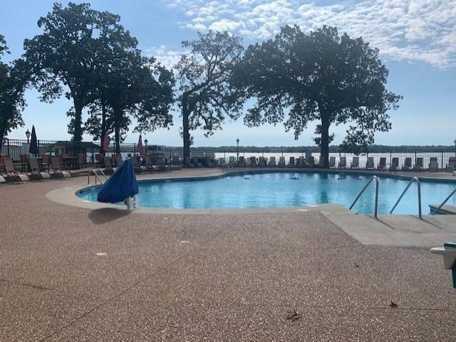 view of swimming pool with a water view and a patio area