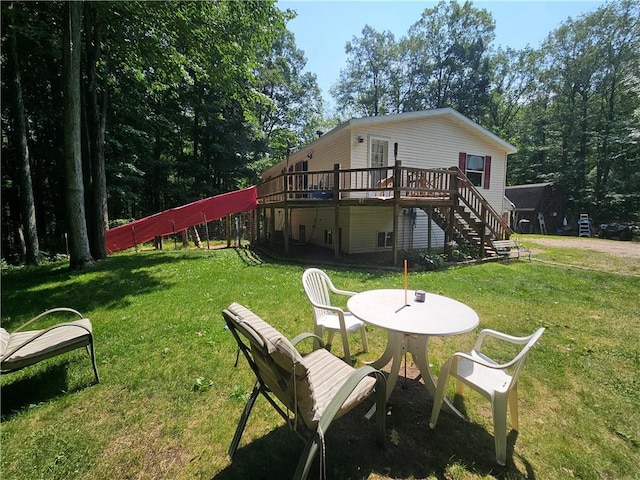 rear view of house featuring a wooden deck and a lawn