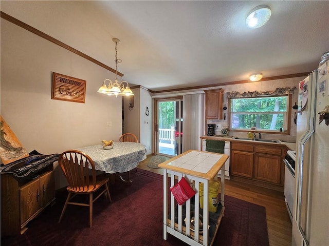 kitchen featuring a healthy amount of sunlight, tile countertops, white appliances, and decorative light fixtures