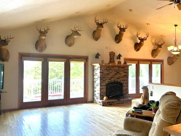 living room featuring ceiling fan with notable chandelier, wood-type flooring, a fireplace, and vaulted ceiling