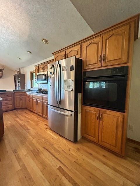 kitchen featuring stainless steel appliances, a textured ceiling, and light wood-type flooring