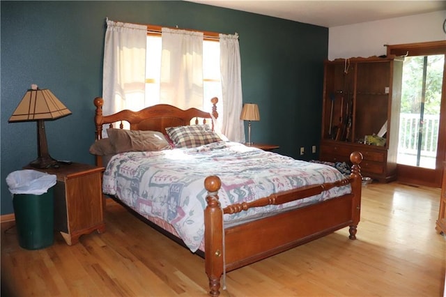 bedroom with multiple windows, wood-type flooring, and access to exterior