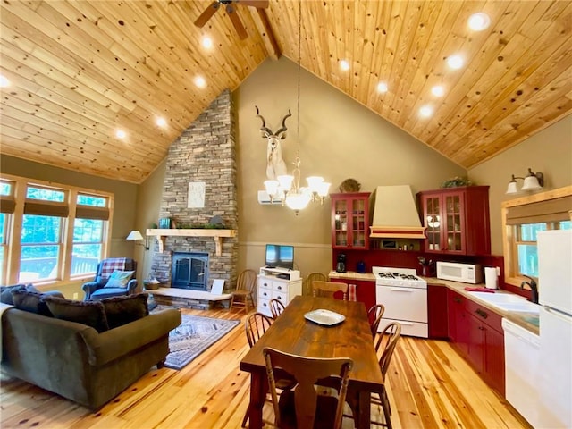 dining room featuring a stone fireplace, wood ceiling, high vaulted ceiling, light wood-type flooring, and beamed ceiling