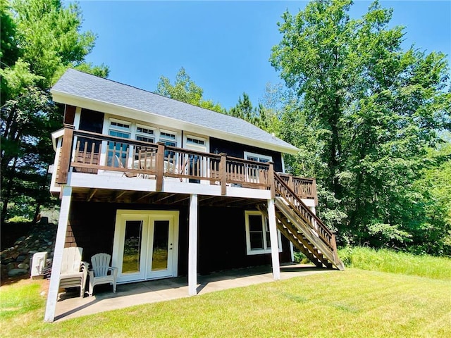 rear view of property featuring a wooden deck, french doors, a patio area, and a lawn