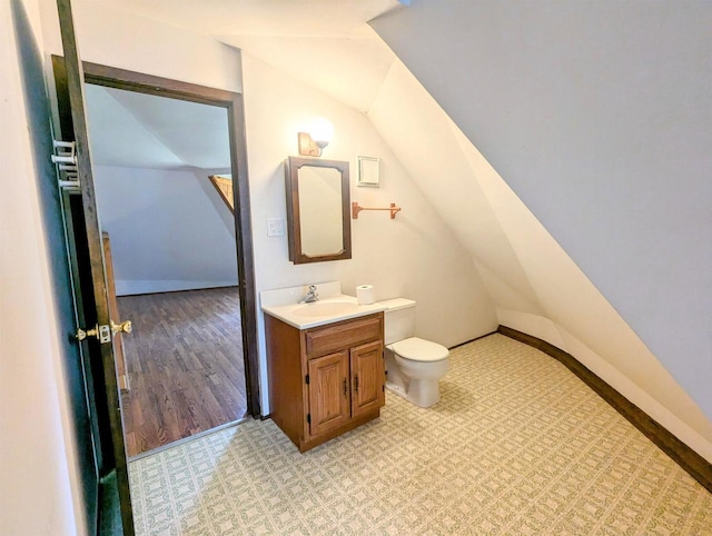 bathroom with vaulted ceiling, hardwood / wood-style floors, vanity, and toilet