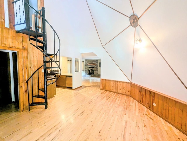 interior space with a stone fireplace, light wood-type flooring, and wood walls