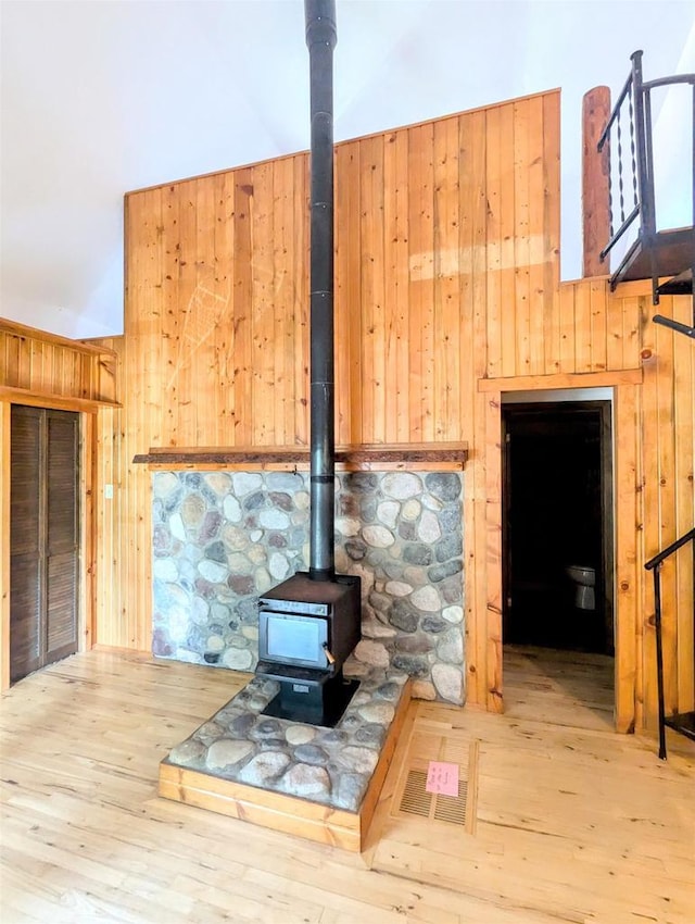 living room with wooden walls, wood-type flooring, and a wood stove