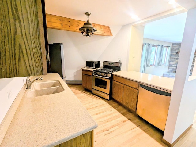 kitchen featuring sink, hanging light fixtures, baseboard heating, stainless steel appliances, and light hardwood / wood-style floors