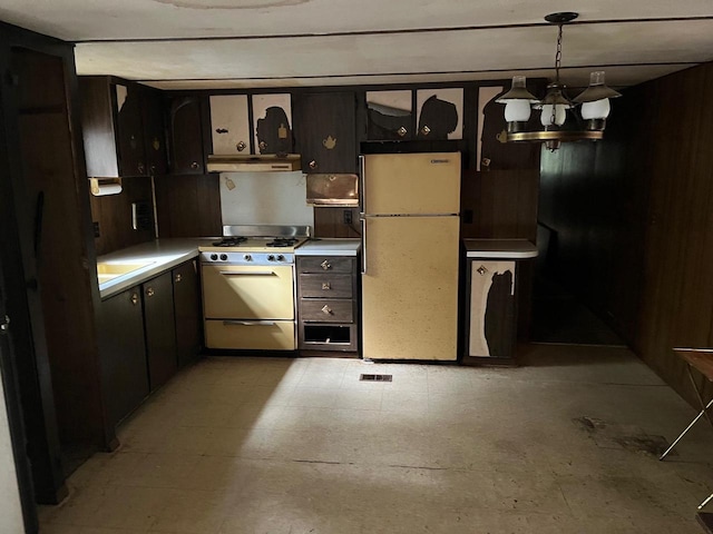 kitchen featuring dark brown cabinetry, gas range, decorative light fixtures, fridge, and a notable chandelier