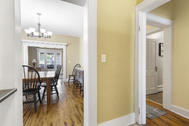 corridor with an inviting chandelier, hardwood / wood-style floors, and baseboard heating