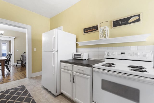 kitchen with tasteful backsplash, white cabinetry, light tile patterned floors, and white appliances