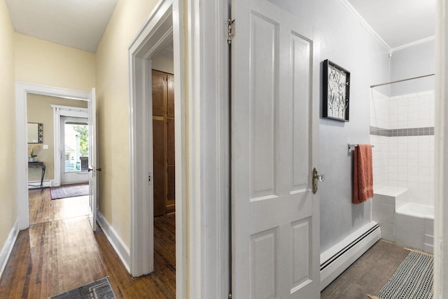 hallway with ornamental molding, a baseboard heating unit, and dark wood-type flooring