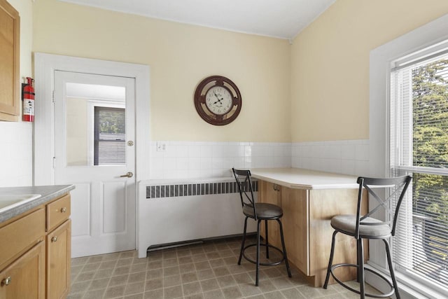 dining area featuring radiator heating unit and tile walls