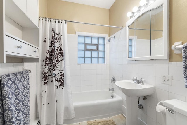 bathroom with shower / tub combo with curtain, toilet, and tile walls