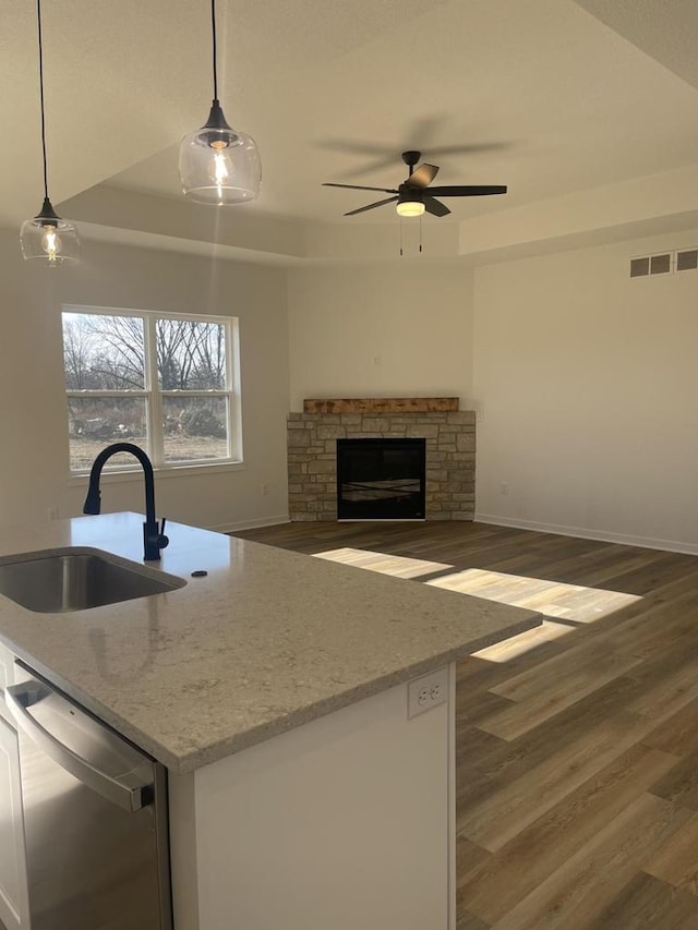 kitchen featuring pendant lighting, dishwasher, sink, dark hardwood / wood-style flooring, and light stone countertops