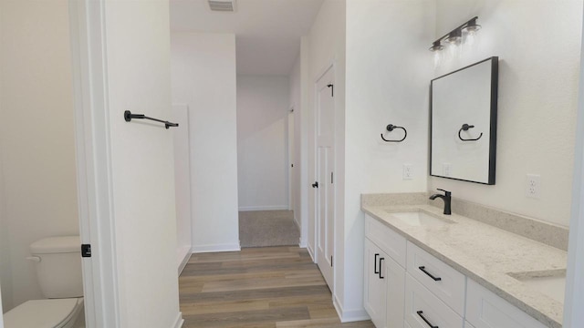 716 Kelsey Rd, Beloit, WI 53511 - bathroom with a sink, toilet, wood finished floors, visible vents, and double vanity