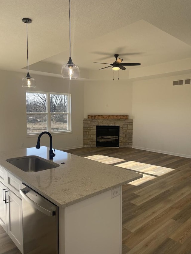 kitchen featuring pendant lighting, sink, light stone counters, white cabinets, and stainless steel dishwasher